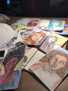 a handful of colorful illustrated portraits on a table.